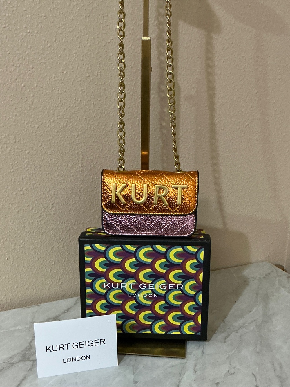 Kurt Geiger London Micro Kensington Kurt Bag in a metallic orange and pink color